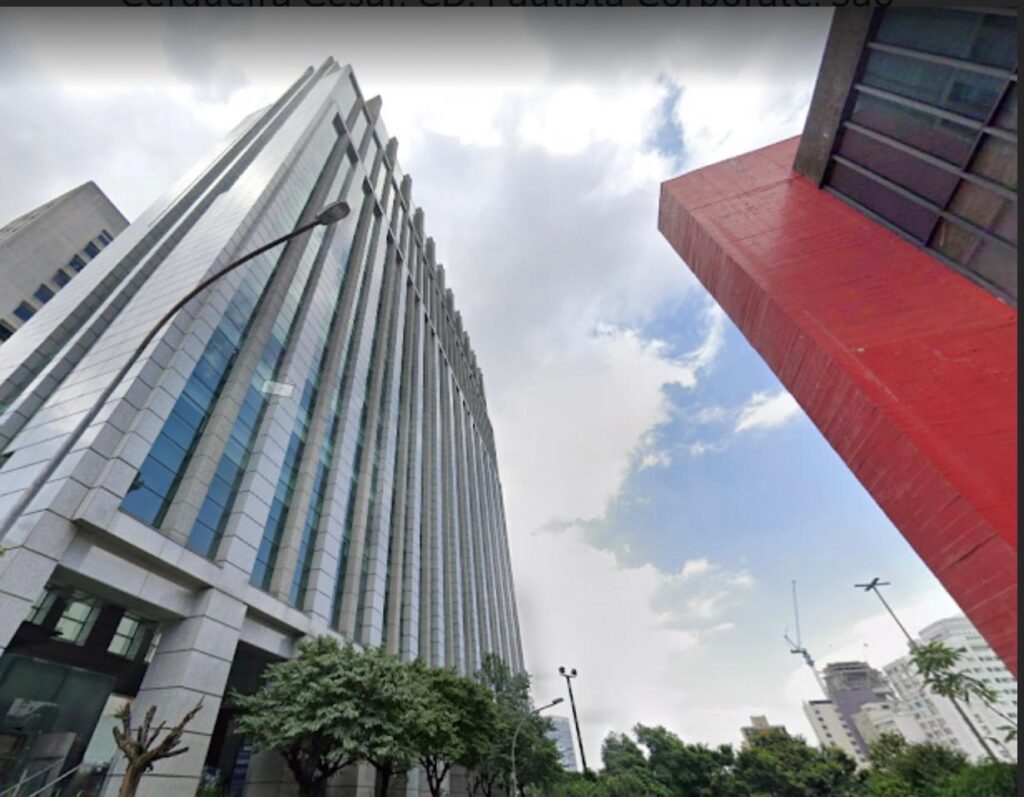 Um edifício vermelho próximo a um prédio alto ilustra a paisagem urbana e moderna, representando a sofisticação da JF Advocacia.